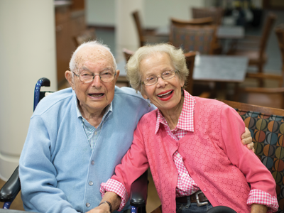 A smiling senior man and woman seated on a bench