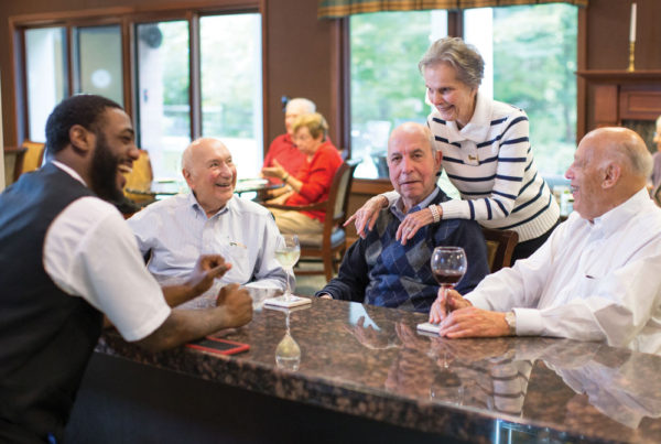 Four seniors gathered at a bar, having drinks and sharing a laugh with the bartender